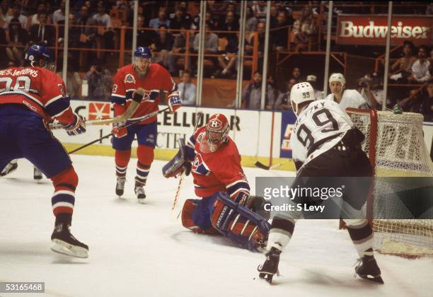 Canadian professional hockey player Patrick Roy goalie of the Montreal Canadiens makes a save while fallen on the ice against Wayne Gretzky of the...