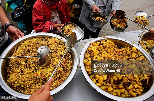 Teachers spoon out free lunch for students at Yuanbao school of Longli country on May 13 in Guizhou, China. Guizhou is a mountainous province located...