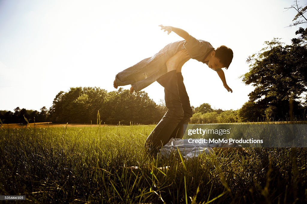 Boy playing with father in field