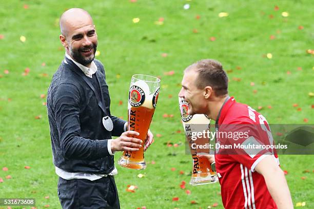 Head coach Josep Guardiola of Bayern Muenchen toast glasses with Holger Badstuber of Bayern Muenchen as they celebrate the Bundesliga champions after...