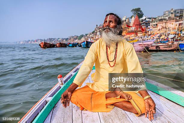 sadhu est une méditation en bateau sur le fleuve gange, sacrée de varanasi - gourou photos et images de collection