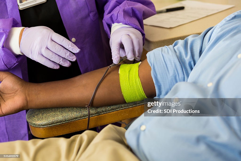 Phlebotomist checking line of patient donating blood in hospital