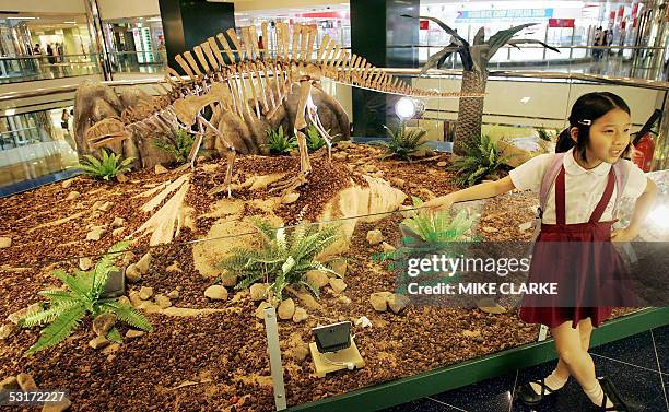 Visitors to a shopping mall have their pictures taken with a Lotosaurus Adentus Dinosaur part of an exhibition on loan from Beijing's Natural History...