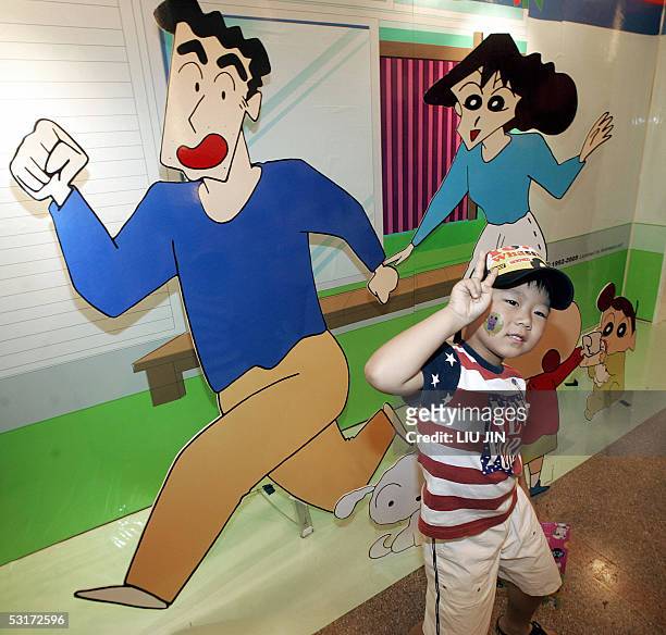 Boy flashes the "V" sign as he poses for a photo in front Japanese cartoon characters ad board at an animation fair in Shanghai, 30 June 2005. AFP...