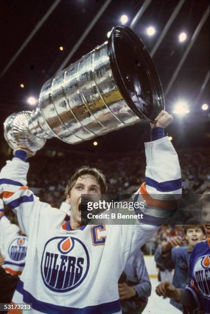 Canadian professional hockey player Wayne Gretzky of the Edmonton Oilers, holds the Stanley Cup aloft as he skates a victory lap around the...