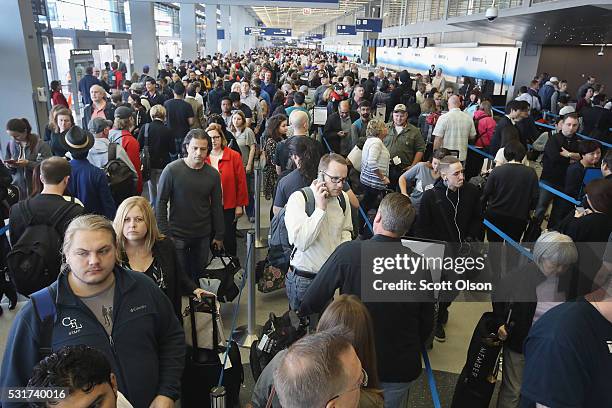 Passengers at O'Hare International Airport wait in line to be screened at a Transportation Security Administration checkpoint on May 16, 2016 in...