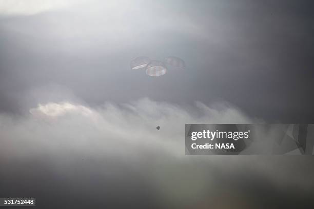 In this handout provided by the National Aeronautics and Space Administration , SpaceXs Dragon spacecraft returns to Earth with a parachute-assisted...