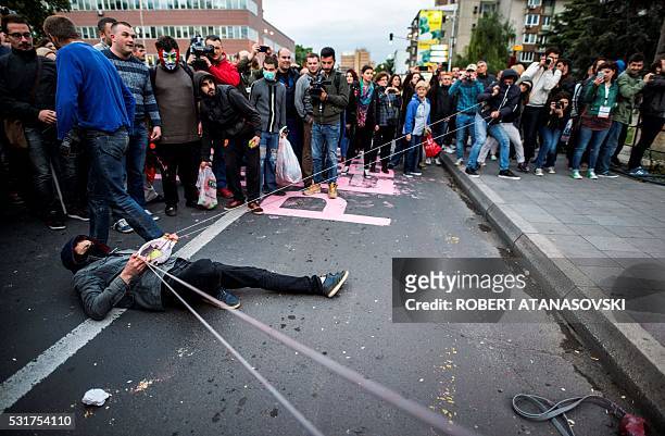 Protestors use an improvised slingshot to throw balloons filled with colored paint toward the Parliament building, during an anti-government protest...