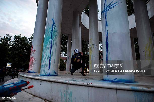 Protestor wearing a mask uses a water gun to spray colored paint on marble columns of a monument, during an anti-government protest in Skopje on May...