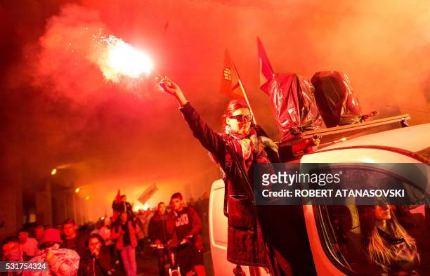 Protestors light flares and wave flags marching through a street, during an anti-government protest, in Skopje on May 16 in series of protests dubbed...
