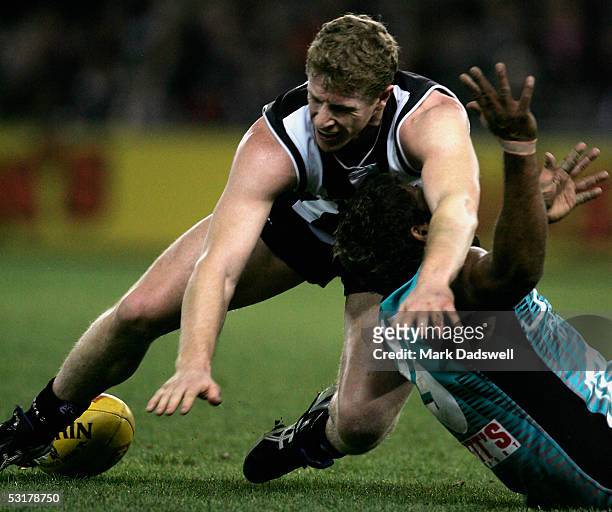 Scott Burns for the Magpies hits Byron Pickett for the Power during the AFL Round 14 match between the Collingwood Magpies and the Port Adelaide...