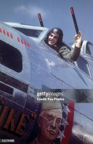 An American airman, stationed in Britain, waves from the cockpit of a B-17 Flying Fortress bomber emblazoned with a picture of U.S. General Dwight D....