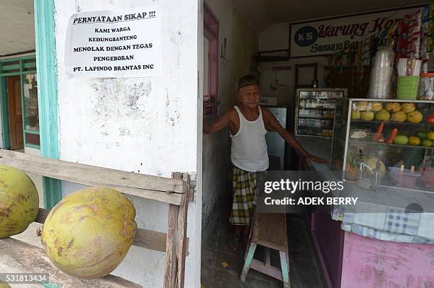 This picture taken on March 28, 2016 shows an Indonesian man standing inside his food stall with a sign displayed on the wall reading "We are...