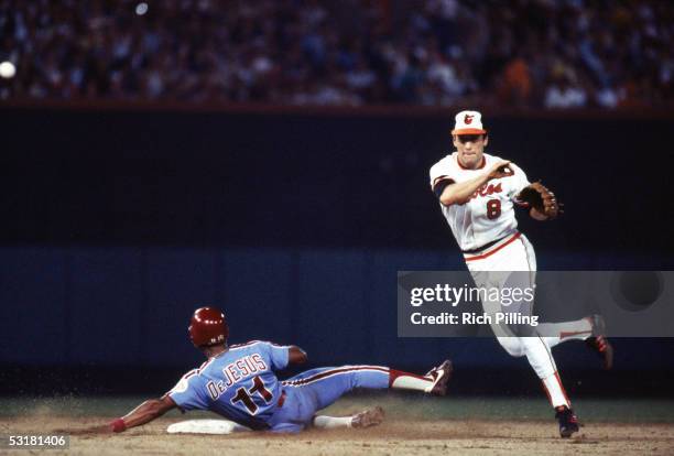 Cal Ripken, Jr. #8 of the Baltimore Orioles attempts to complete a double play as he throws over Ivan DeJesus of the Philadelphia Phillies during a...