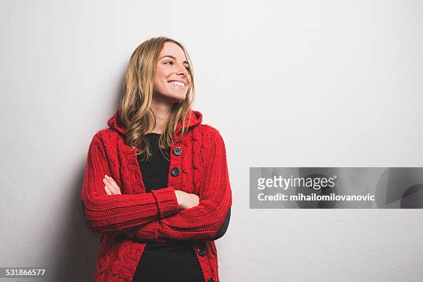 young woman posing against the wall - red cardigan sweater stock pictures, royalty-free photos & images