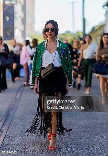 Guest wearing a green bomber jacket, red heels and black skirt with fringes outside Bec & Bridge at Mercedes-Benz Fashion Week Resort 17 Collections...