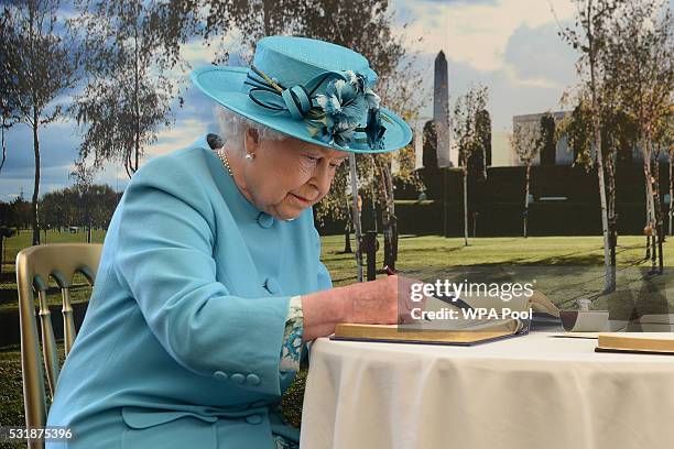 Queen Elizabeth II signs the visitor book following a service paying tribute to soldiers from the Duke of Lancaster's Regiment killed while serving...