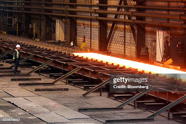 An employee watches as a roll of hot steel passes along a conveyor belt inside Liberty House Group's rolling steel mill in Newport, U.K., on Tuesday,...