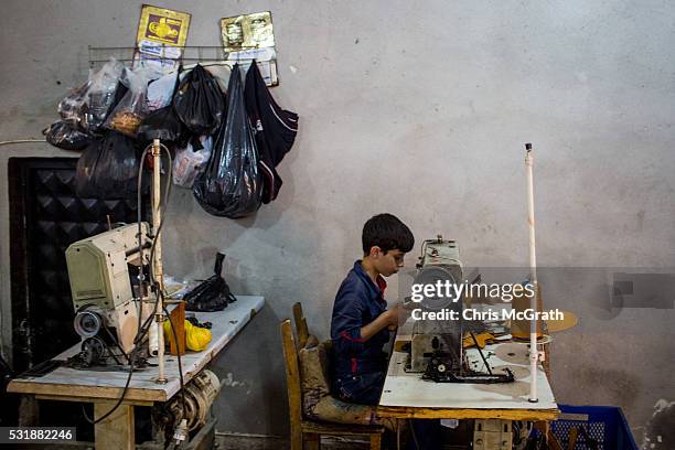 Young Syrian refugee boy makes shoe parts in a Turkish owned factory on May 16, 2016 in Gaziantep, Turkey. Since fleeing the war and after the new...