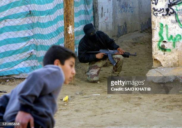 Palestinian boy takes a look while a gunman is on alert during an Israeli army operation in the Rafah refugee camp in southern Gaza Strip 08 February...