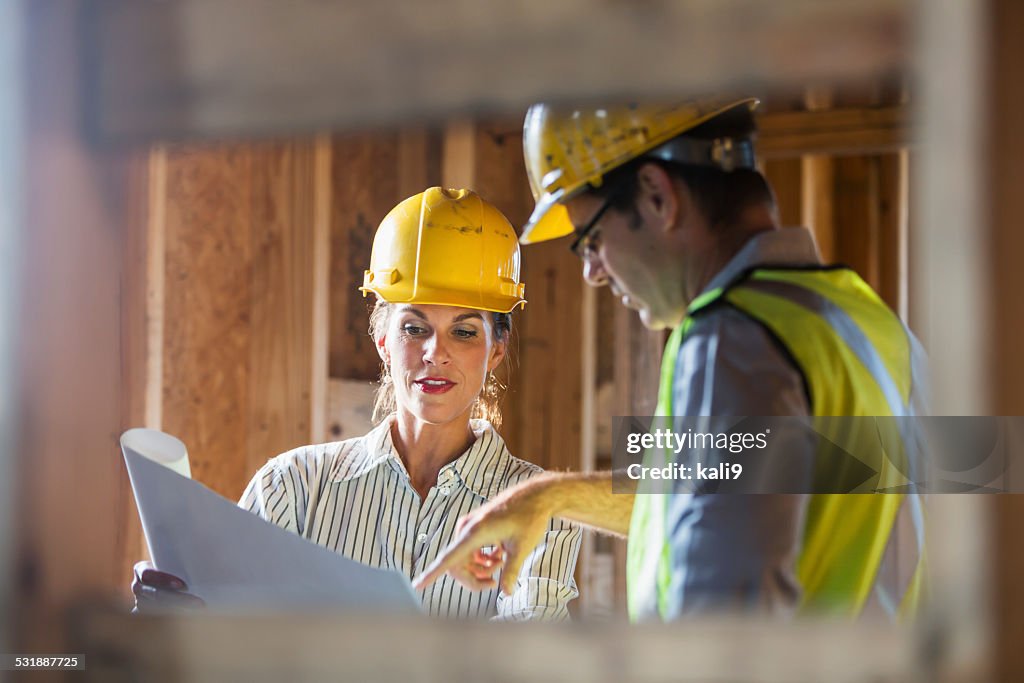 Arbeiter, die auf der Baustelle Pläne überprüfen.