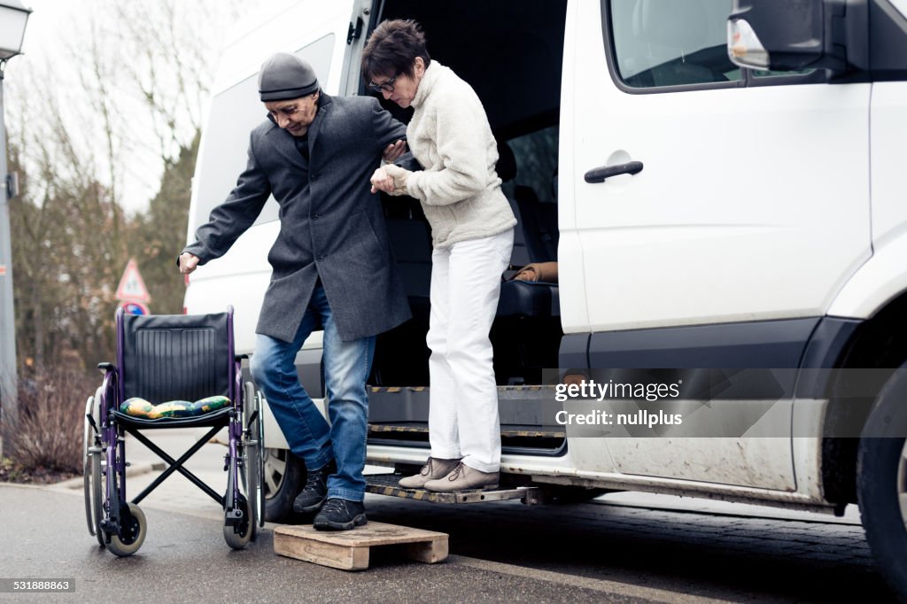 Nurse helping senior man exit a van