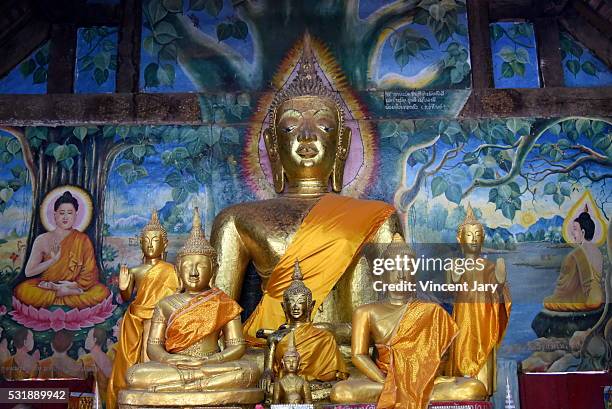 buddha statues and wall paintings aham outama thany temple luang prabang laos - luang prabang stock illustrations