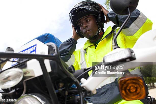 An emergency medical technician puts on a helmet before riding on a USAID donated motorcycle equipped with a sidecar gurney outside of the Manzanillo...