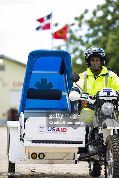 An emergency medical technician sits on a USAID donated motorcycle equipped with a sidecar gurney for a photograph outside of the Manzanillo Fire...