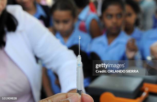 Health Ministry employee prepares to vaccinate girls against the human papilloma virus in Tegucigalpa, on May 17, 2016. - The government wants to...