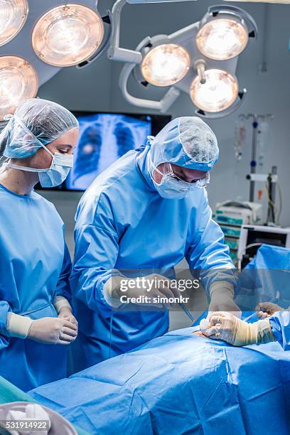 surgeons performing surgery - man lying on operating table stock pictures, royalty-free photos & images