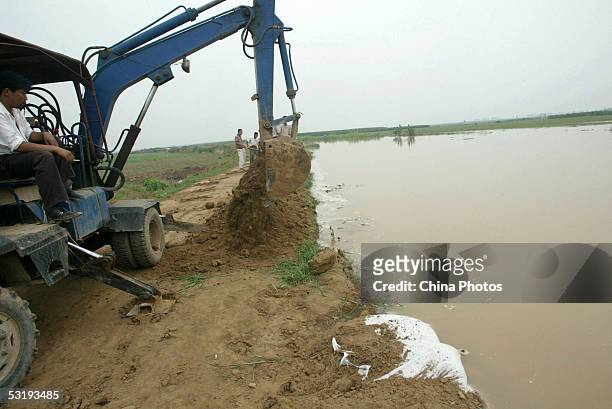 Villager uses a scraper to scoop earth reinforcing the bank of Weihe River before the coming of the flood peak July 4, 2005 in Huaxian County of...
