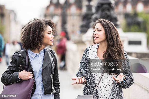 two female friends talking outdoors in paris, france - walking street friends stock pictures, royalty-free photos & images