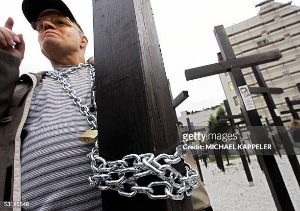 Man has chained himself at a wooden cross, 05 July 2005 at a memorial at the former Checkpoint Charlie in Berlin, in a protest against the removal of...