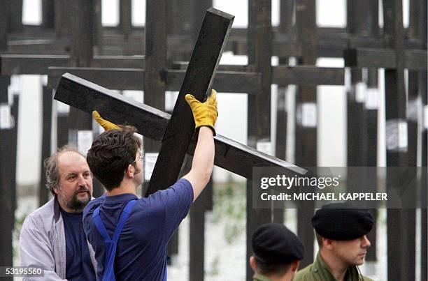 Workers dismantle wooden crosses under the eye of the police, 05 July 2005 at a memorial at the former Checkpoint Charlie in Berlin, during the...