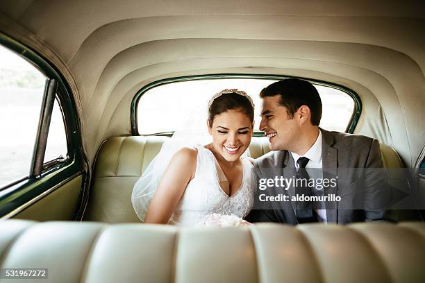 beautiful hispanic newlyweds laughing in backseat - front on groom and bride stock pictures, royalty-free photos & images