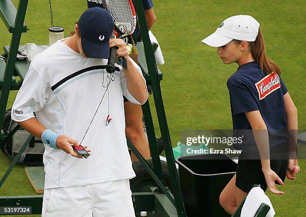 Ballgirl looks over to see what Andrew Murray of Great Britain is playing in his IPod before his match against Gregory Carraz of France on July 5,...