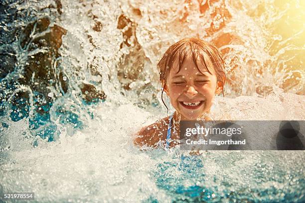 niña pequeña jugando en cascada en parque acuático piscina - tobogán de agua fotografías e imágenes de stock