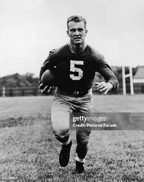 University of Notre Dame student Paul Hornung, quarterback for the university's football team, runs down a football field with the ball, mid 1950s....