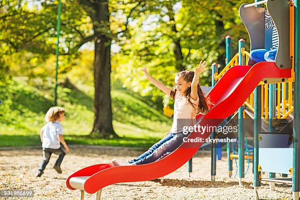 niña divirtiéndose mientras corredizas. - área de juego fotografías e imágenes de stock