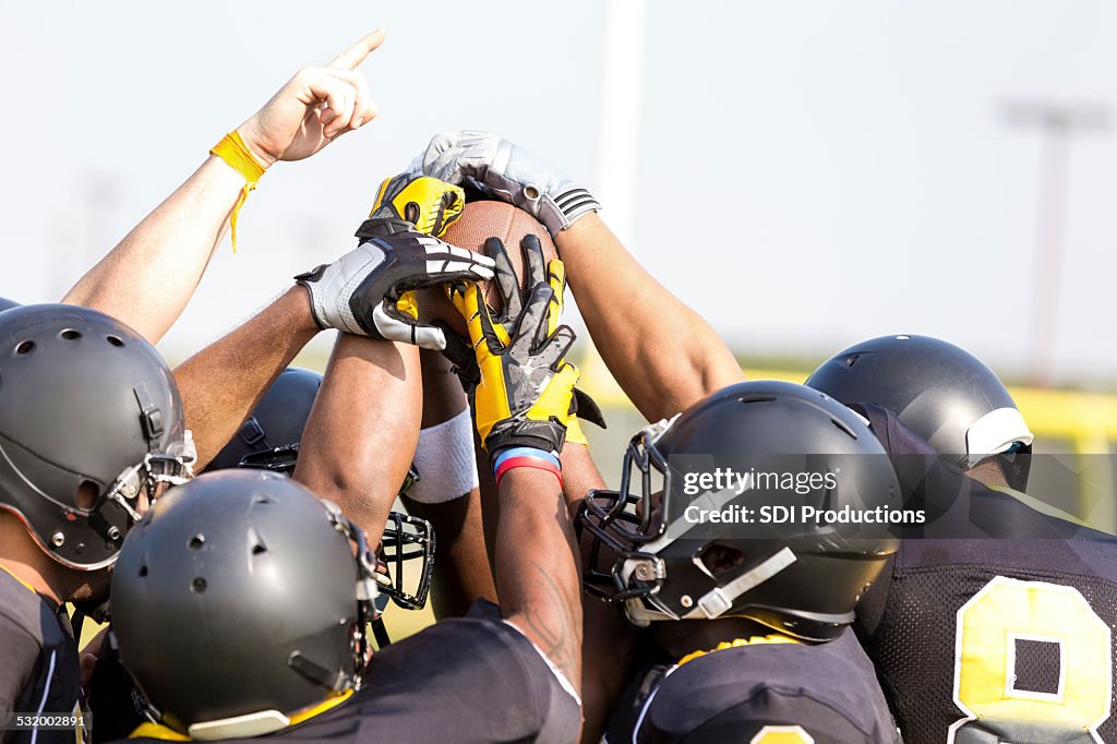 Professional football players holding ball on sidelines at stadium