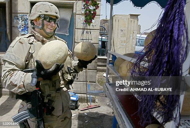 Soldier buys watermelon as his colleagues secure the scene where a roadside bomb exploded in Baghdad, 06 July 2005. No casualties were reported in...