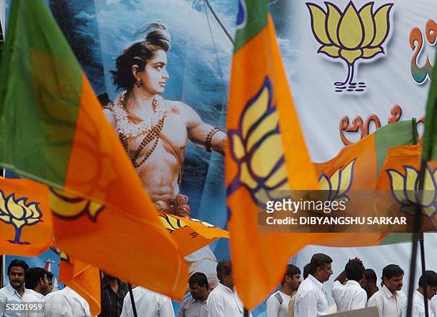 Activists of the Bhartiya Janta Party wave party flags in front of a bill-board depicting the Hindu God, Ram during a protest rally organised by the...