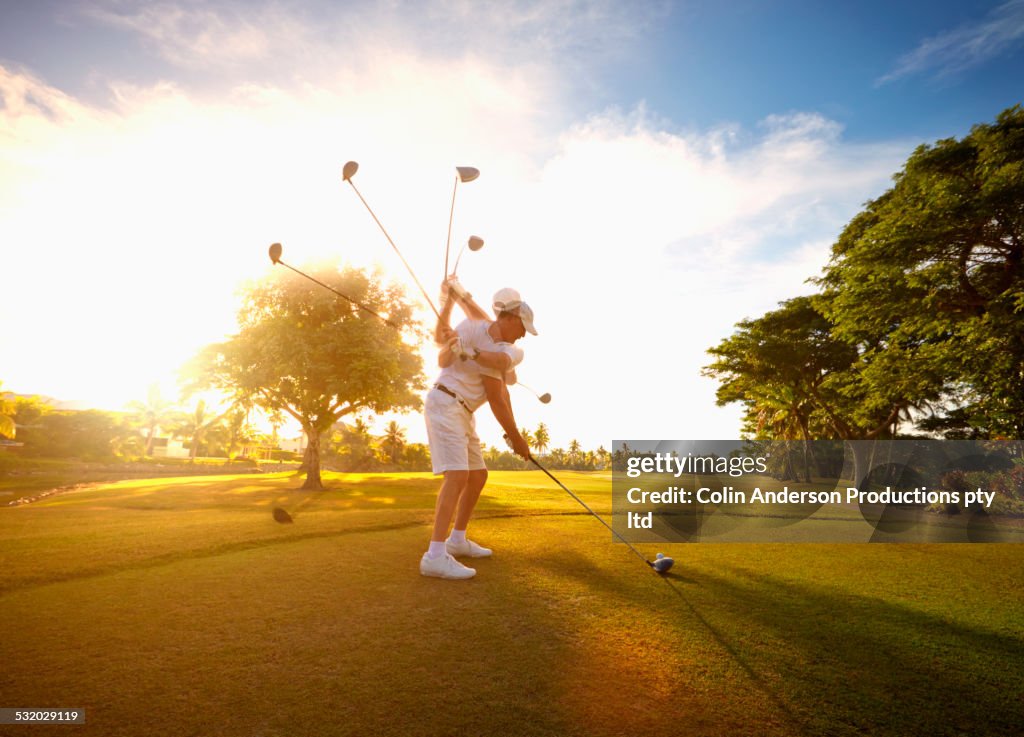 Multiple exposures of Caucasian golfer hitting ball on course