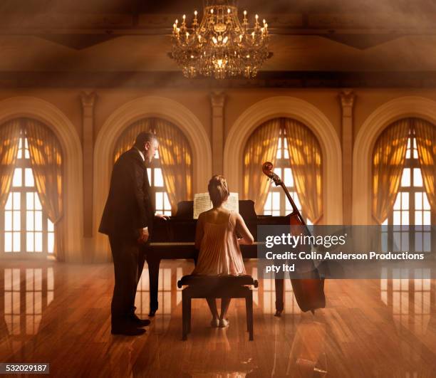 caucasian music teacher and student at piano in ballroom - fabolous musician stockfoto's en -beelden