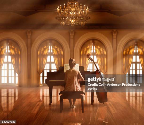 caucasian girl playing piano in ballroom - balzaal stockfoto's en -beelden