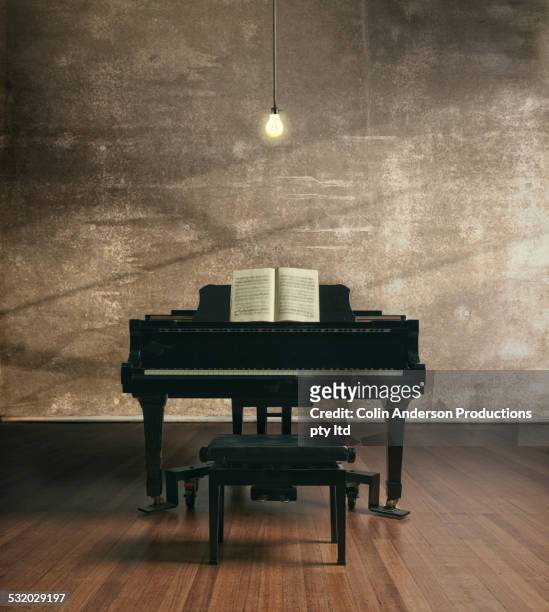 piano under illuminated light bulb - piano stock pictures, royalty-free photos & images