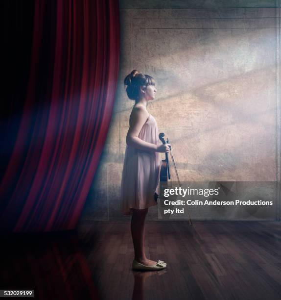 caucasian girl holding violin on stage - violine stock-fotos und bilder