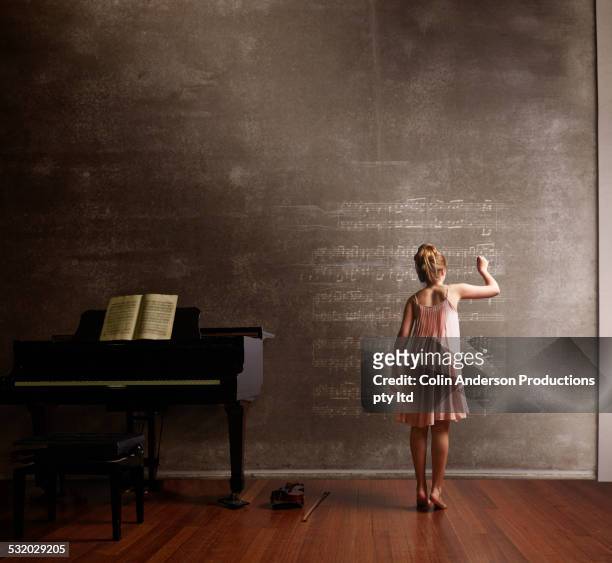 caucasian girl writing music on blackboard - melody anderson stock-fotos und bilder