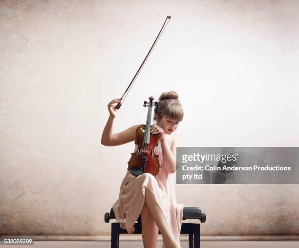 caucasian girl tuning violin on bench - melody anderson stock-fotos und bilder